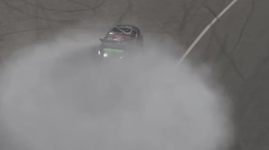 Drift Donut Smoke - An aerial view looking down at a single car spinning in circles and performing a burnout, generating a thick, circular cloud of white tire smoke on a grey track