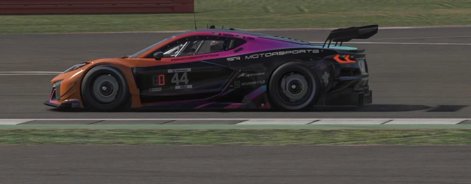 Side profile of #44 Chevrolet Corvette C8.R with custom orange pink teal black livery showing wheel rotation and aero details